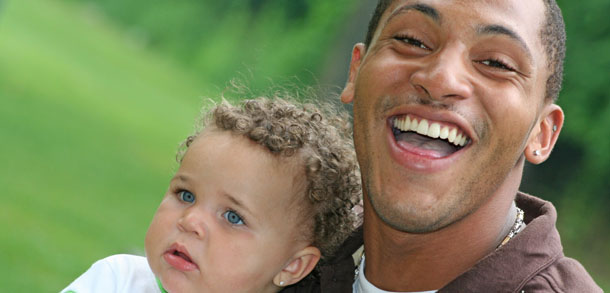 Close-up of adoptive father with infant son, outdoors on a sunny day