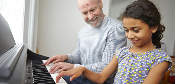 Adoptive father and daughter playing a piano duet