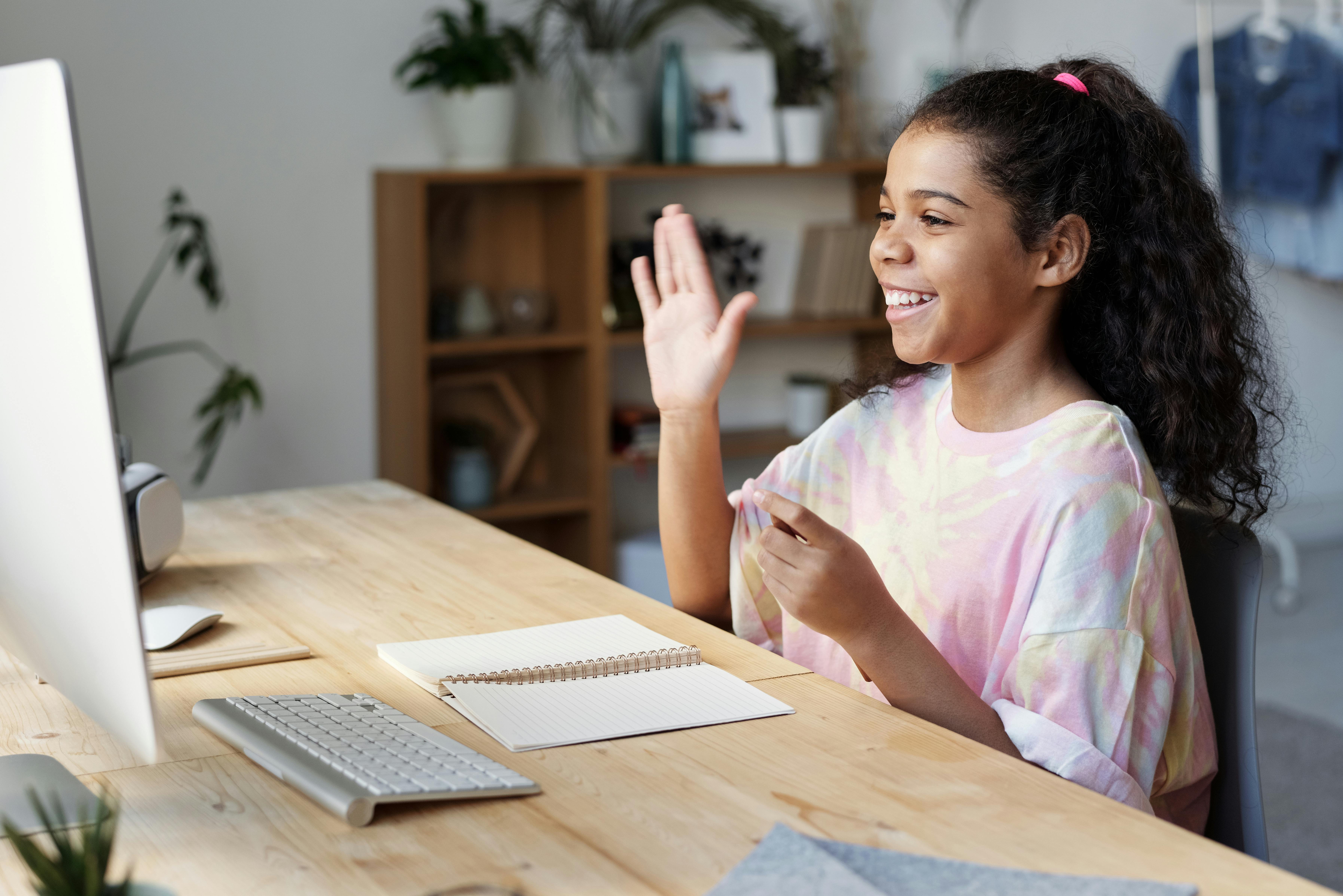 Young girl waving to computer screen