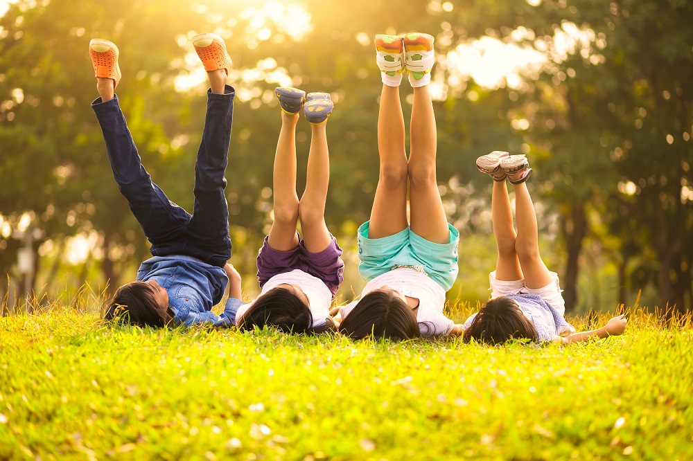 Family of four lying on the grass in a park with their legs raised