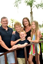 Sam, a foster carer, and her husband and children smiling and hugging